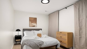 Une chambre à coucher moderne avec un lit, une table de chevet et une commode en bois.