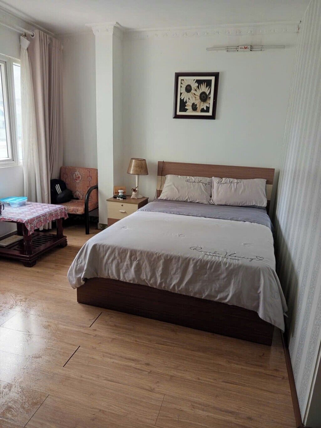 A neatly arranged bedroom with a bed, bedside table, lamp, and a chair.