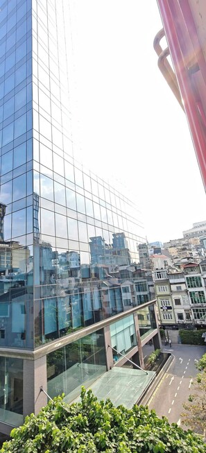 A modern glass building with a reflective facade, surrounded by other buildings and greenery. - Lunaria Maison Japan Town Kitchen Suite (Ho Chi Minh City)