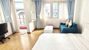 Une chambre d’hôtel avec un lit, un canapé bleu, un bureau et une fenêtre avec des rideaux.