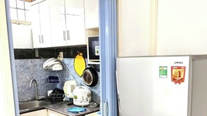 Une cuisine de taille réduite avec des meubles blancs, un réfrigérateur en acier inoxydable et une porte bleue.