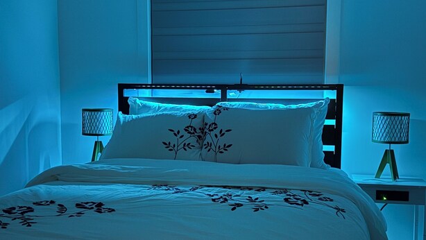 A bedroom with a bed, nightstands, a window with blinds, and a wall-mounted lamp. - Slice of Heaven - Near Spruce Meadows - 2 Car Garage Central AC avail -Sleeps 8  (Calgary)
