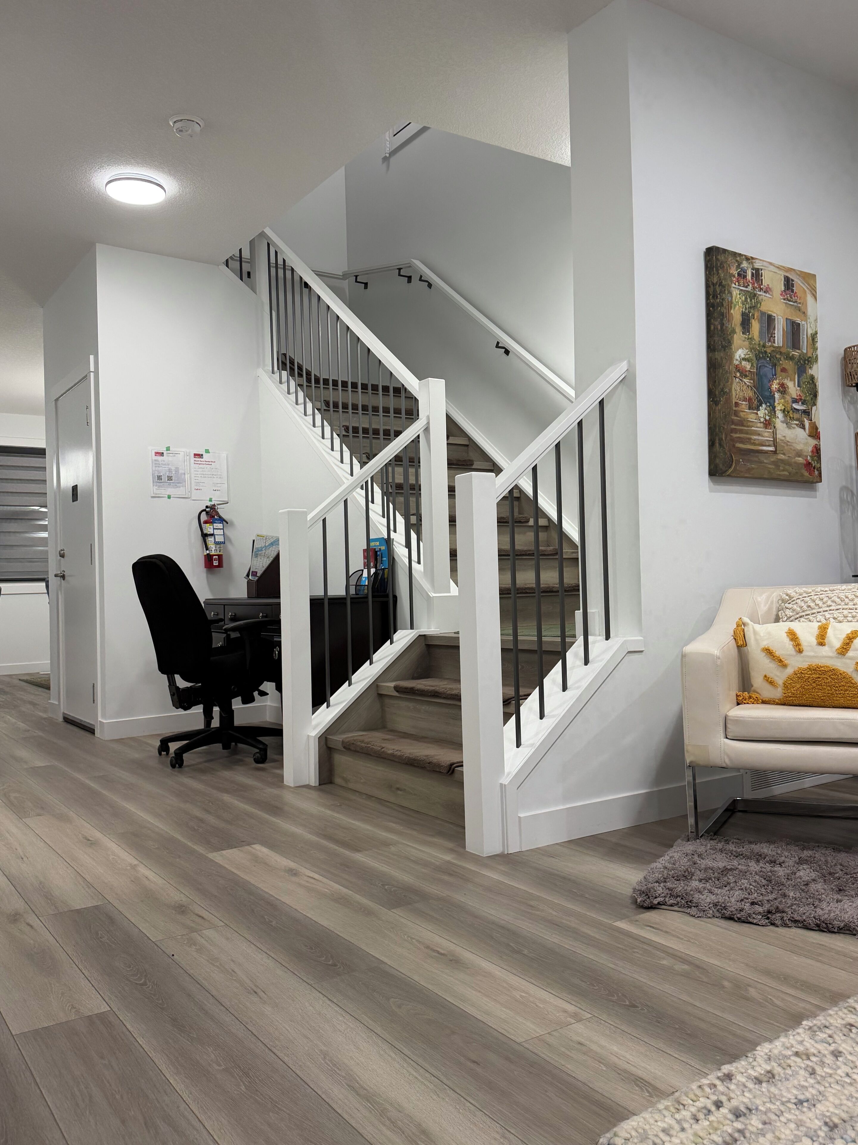 Ein modernes Interieur mit einer Treppe, einem Schreibtisch mit Bürostuhl und einem Gemälde an der Wand.