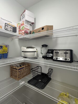 Una cocina con estantes blancos, un tostador, una licuadora y una cesta.
