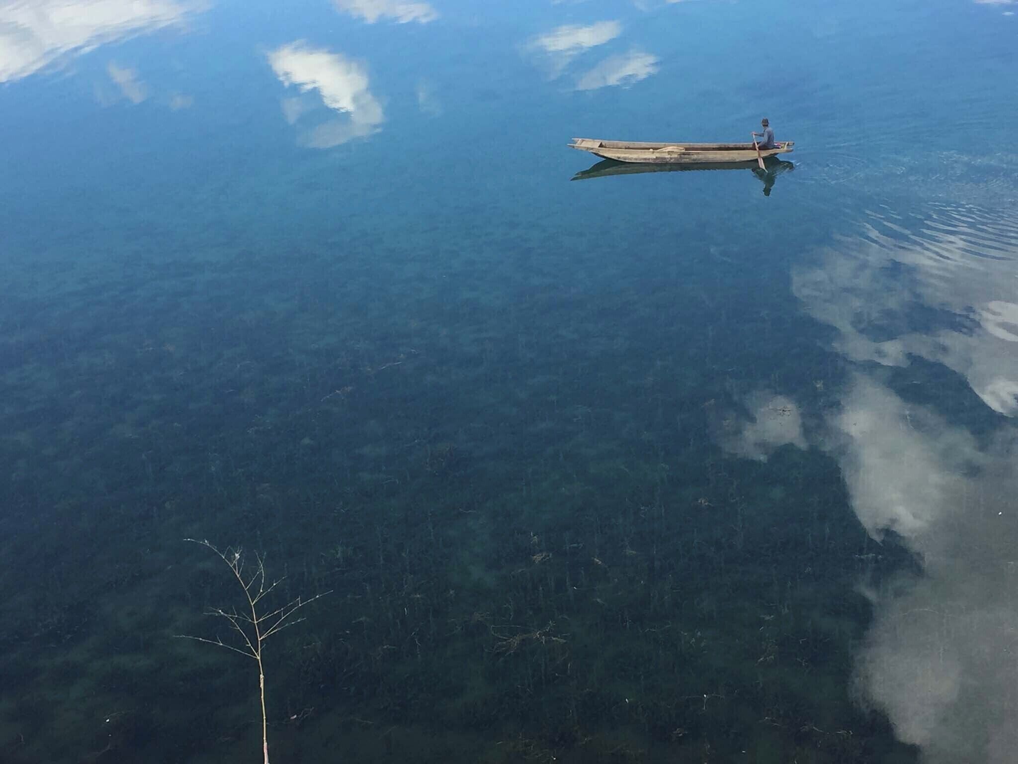 A calm body of water with a small wooden boat.
