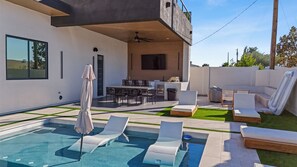 A modern outdoor pool area with lounge chairs, a dining table, and a ceiling fan. - Scottsdale 6BR Luxury Home Heated Pool Spa Sleeps 13 (Scottsdale)