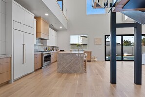 A modern kitchen with wooden cabinets, a marble island, and a large window overlooking a pool. - Scottsdale 6BR Luxury Home Heated Pool Spa Sleeps 13 (Scottsdale)