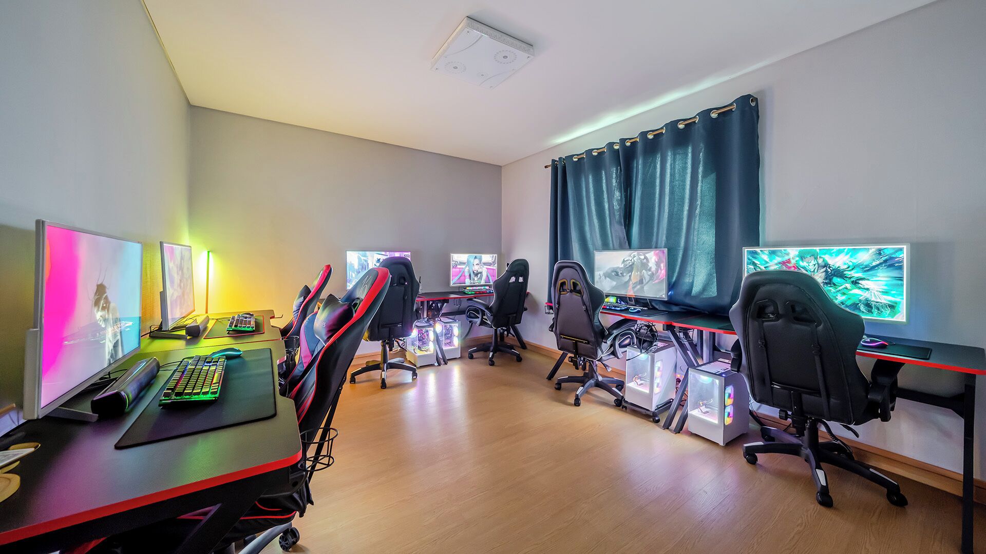 A gaming room with multiple gaming stations, each with a monitor, keyboard, and chair.