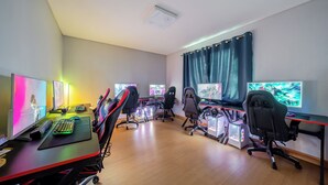 Een speelruimte met meerdere gaming stations, elk met een monitor, toetsenbord en stoel.