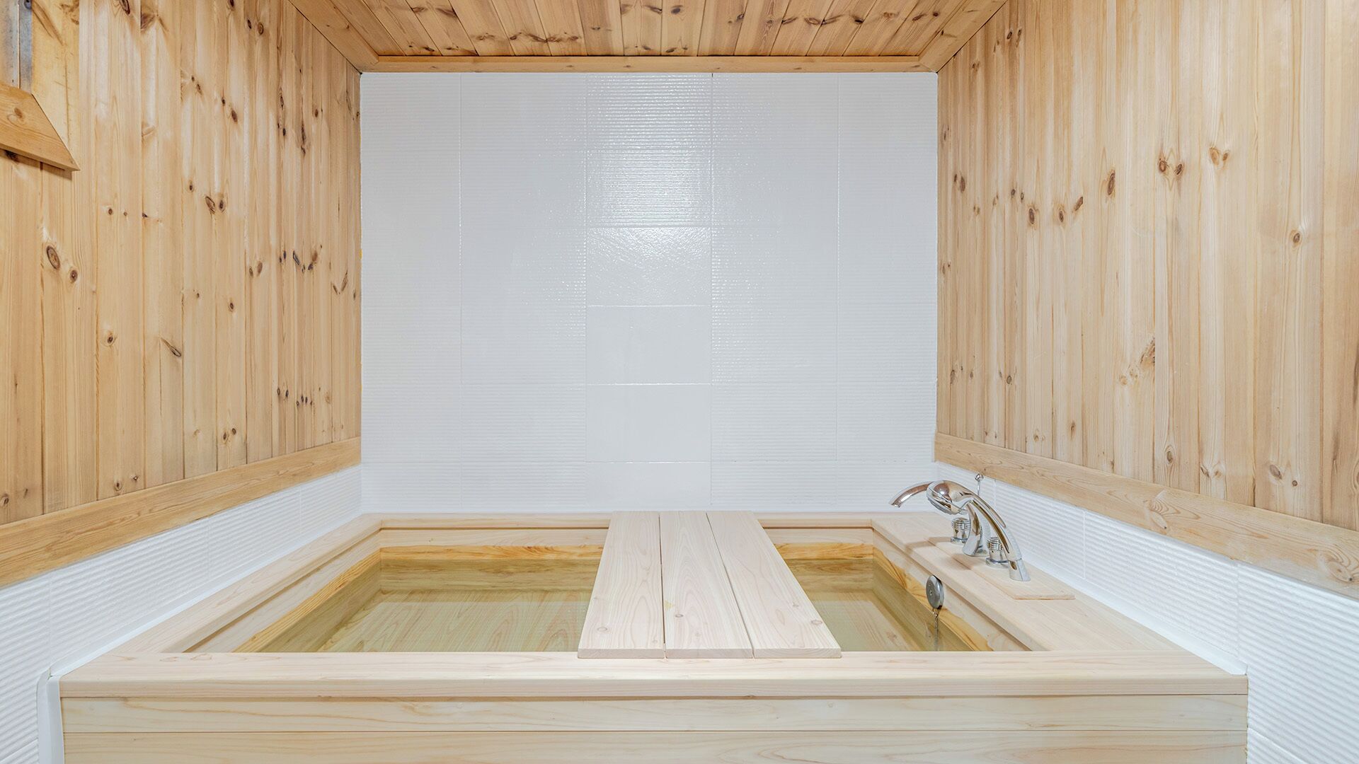 A wooden sauna with a rectangular tub and a single faucet.