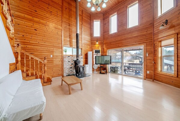 A wooden interior with a staircase, a sofa, a TV, and a fireplace. - Yangpyeong Narinsoom Private Villa (Yangpyeong)