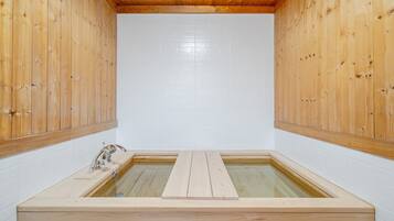 A wooden sauna with a rectangular shape, white tiled walls, and a wooden bench in the center.