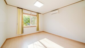 Een kamer met een groot raam, een plafondlamp en een airconditioningsunit.