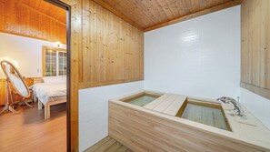 Een houten interieur met een houten badkuip, een bed en een spiegel.