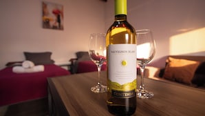 A bottle of sauvignon blanc wine and two glasses on a wooden table in a hotel room.