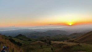 A panoramic view of a hilly landscape during sunset.