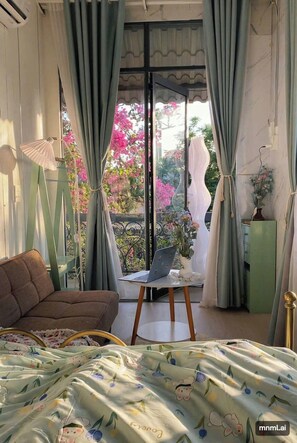 A bedroom with a bed, a chair, a small table, and curtains. - Soluna Pearl Villa Tien Loi Residence  (Tuyen Quang)