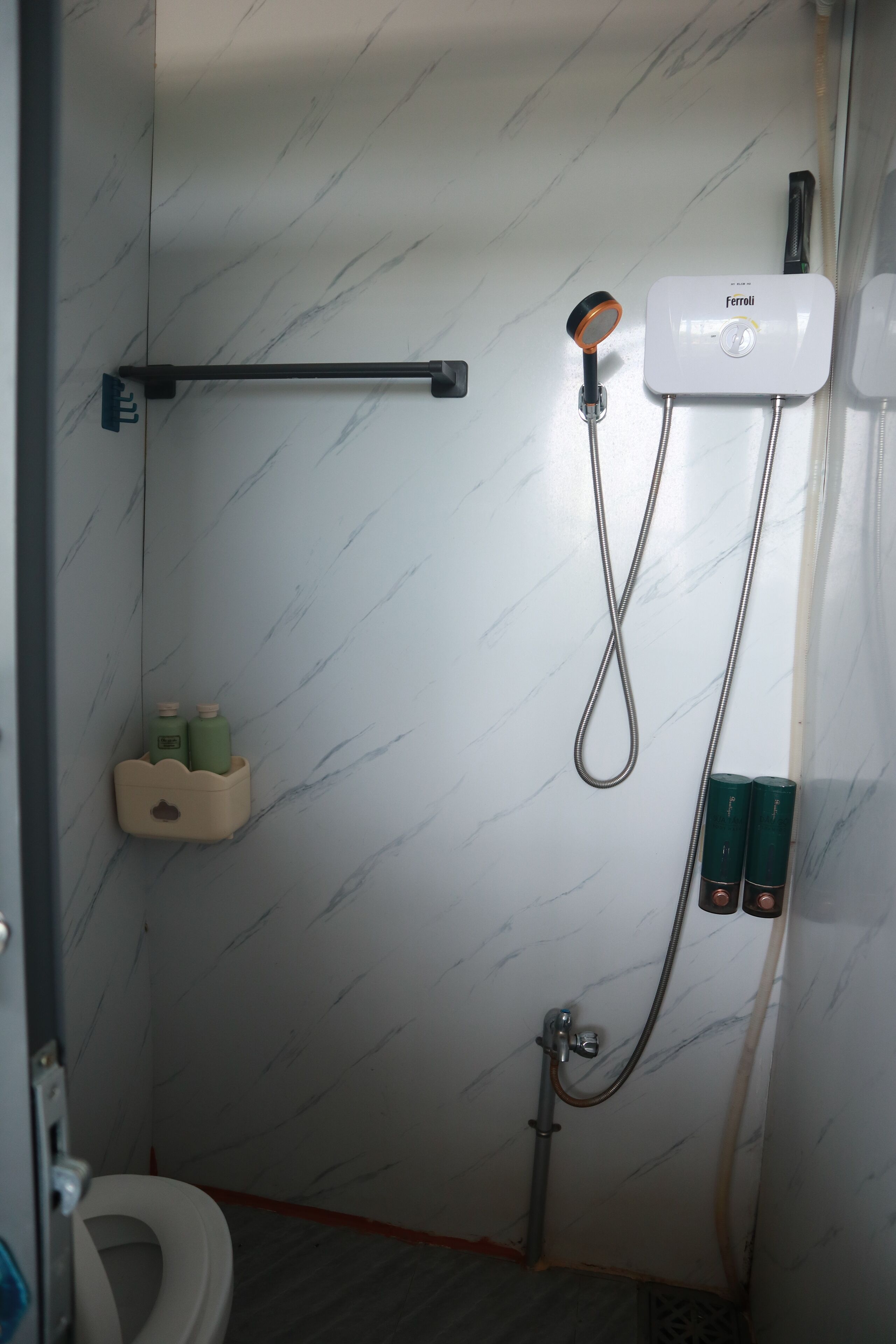 A bathroom with a shower, toilet, and a towel rack.