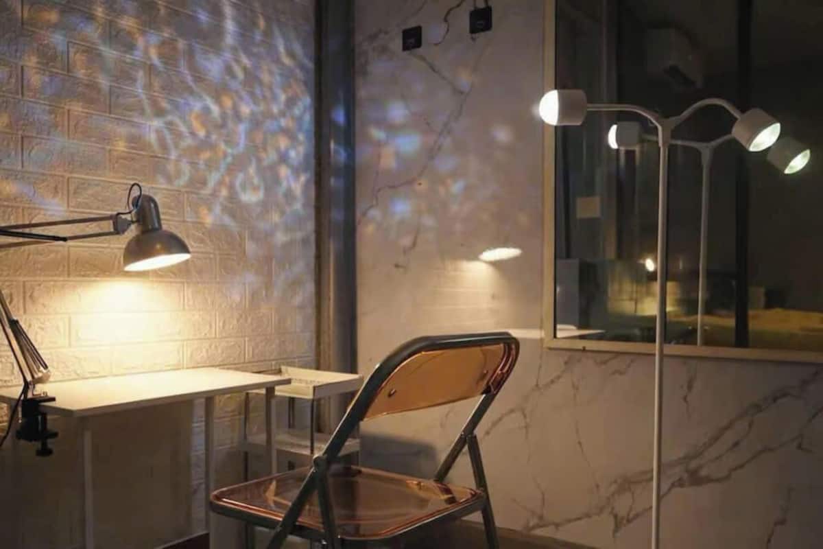 Un espace de travail comprenant un bureau, une chaise et une lampe fixée au mur.