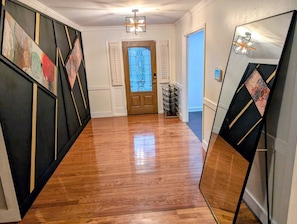 A hallway with wooden flooring, a door with a stained glass window, and a mirror on the right. - The Comfort Haven— Peaceful Stays Made Easy! (Atlanta)