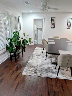 A modern dining room with a dark wood floor, a marble rug, and a table set for six. - The Comfort Haven— Peaceful Stays Made Easy! (Atlanta)