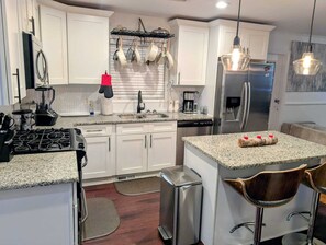 A modern kitchen with white cabinets, stainless steel appliances, and a granite countertop. - The Comfort Haven— Peaceful Stays Made Easy! (Atlanta)