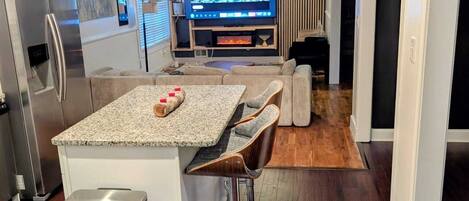 A modern kitchen with a central island, stainless steel appliances, and a flat-screen TV.