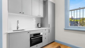 Una cocina moderna con armarios blancos, un lavamanos de acero inoxidable y un horno.