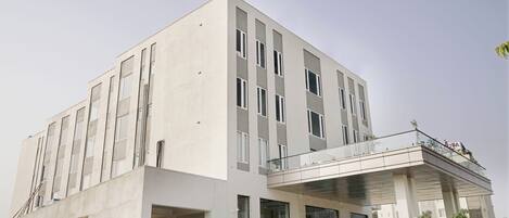 A modern building with a flat facade, large windows, and a covered entrance area with seating.