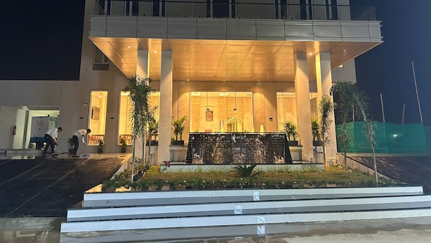 A hotel entrance with a covered walkway, a reception desk, and a water feature in the foreground. - Mastiff Select Aparajita (Danta Ramgarh)