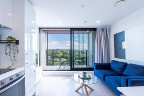 A modern living space with a balcony, a sofa, a glass coffee table, and a kitchen area. - Nice City Studio with Ponsonby View (Auckland City)