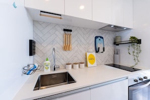 A modern kitchen with a herringbone tile backsplash, stainless steel sink, and a built-in oven. - Nice City Studio with Ponsonby View (Auckland City)
