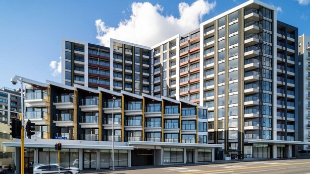 A multi-story building with a modern architectural design, featuring balconies and large windows.