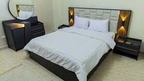 Un dormitorio moderno con una cama grande, mesitas de noche, un espejo y un aparador.
