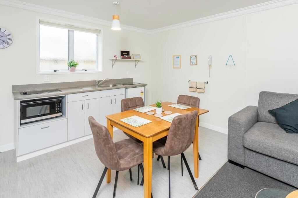 A compact kitchen with a dining table, chairs, a microwave, and a built-in oven.