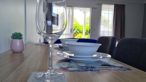 A dining table with a wine glass, plates, and a bowl. - Kings Court Motel (Whanganui)
