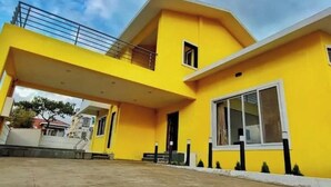 A yellow building with a balcony and a large window.