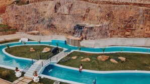 Ein Schwimmbecken mit Wasserfall, umgeben von Gras und Felsen.