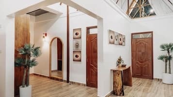 A spacious hallway with wooden flooring, a wooden archway, and a ceiling with skylights.