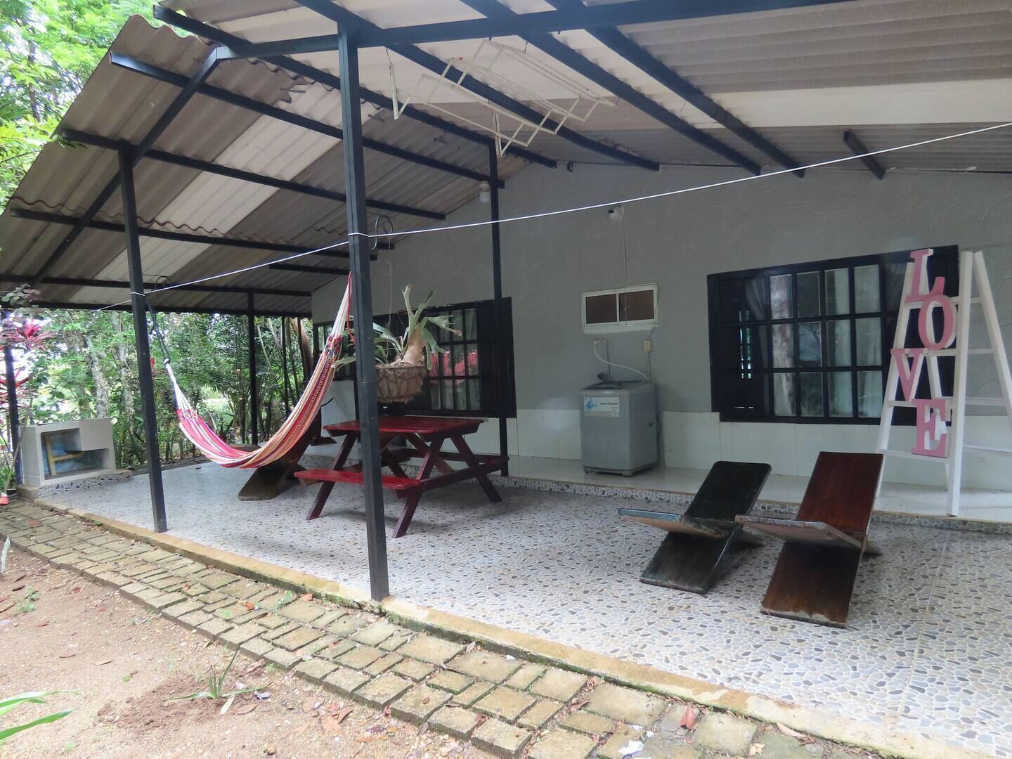 A covered outdoor area with a hammock, a table, and a bench.