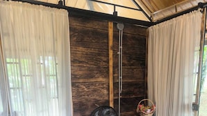 Une pièce avec un fauteuil en osier, un ventilateur sur pied et un haut-parleur.