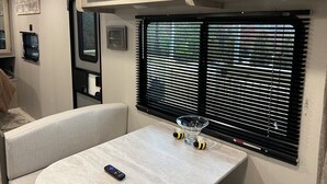 Interior compacto de una caravana, con una kitchenette, una mesa y un control remoto, además de un cuenco de vidrio decorativo.