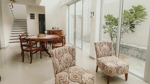 Un'ampia zona giorno con soffitto alto, un tavolo da pranzo con sedie e una scala che conduce a un livello superiore.