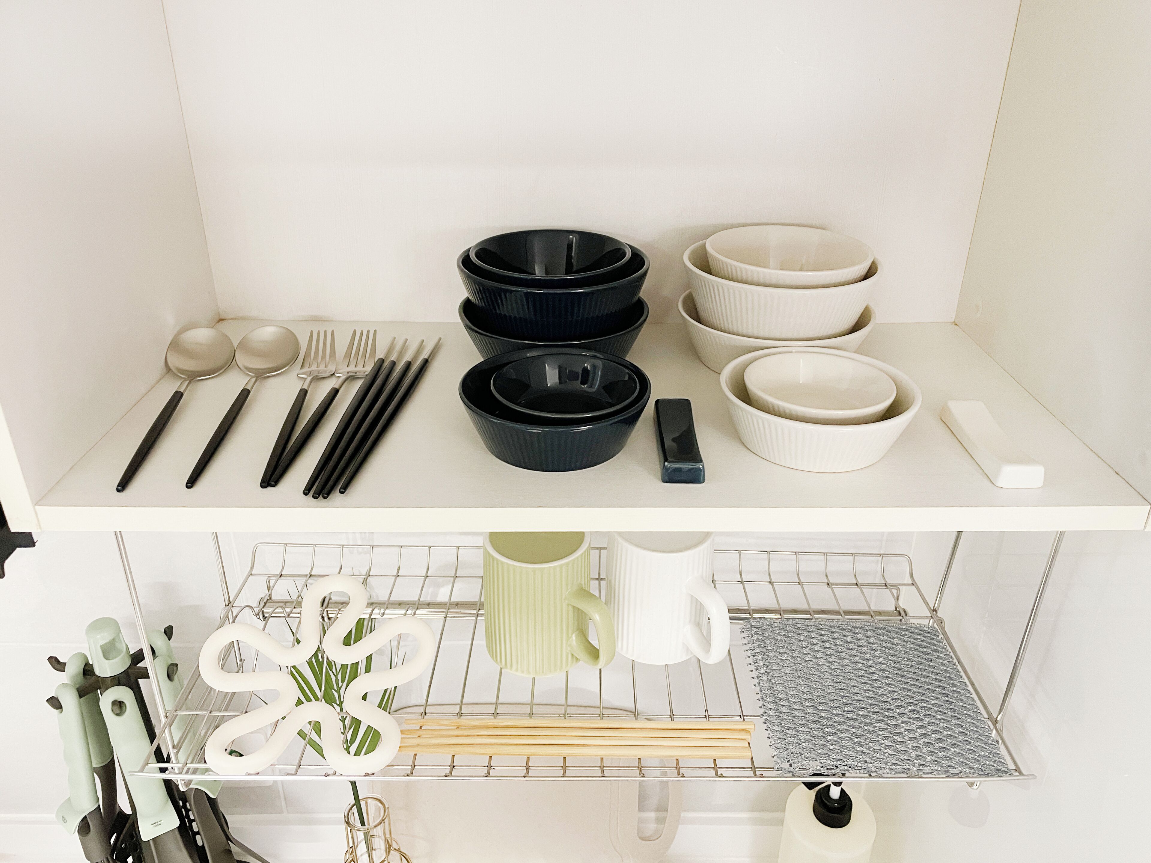 A kitchen with white cabinets, a countertop, and various utensils and cookware.