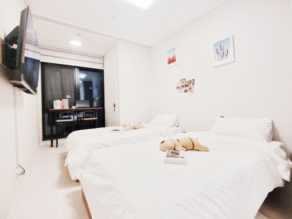 A hotel room with a large bed, a desk with a laptop, and a TV mounted on the wall. - MZstay Seomyeon (Busan)