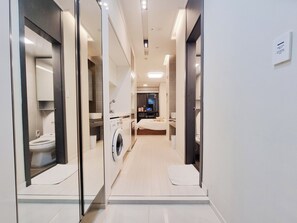 A modern hotel bathroom with a washing machine, a toilet, and a sink. - MZstay Seomyeon (Busan)