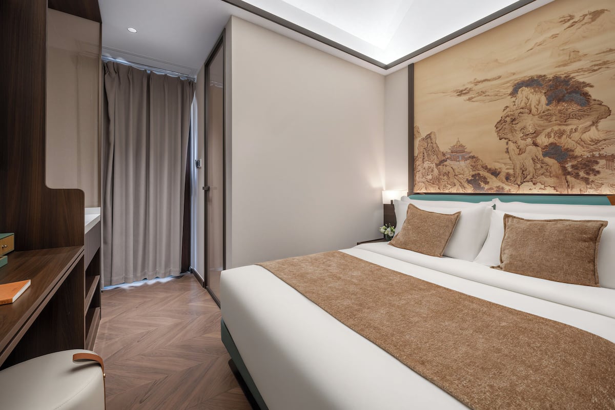 Ein Hotelzimmer mit Bett, Schreibtisch und einem großen Gemälde an der Wand.