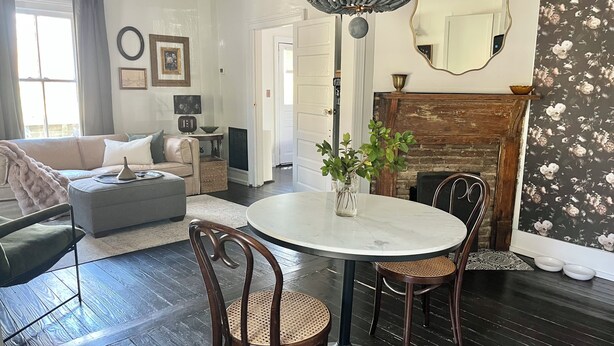 A living room with a round dining table, two wooden chairs, a sofa, and a fireplace. - The Porch Parlor-Historic Oakwood, walkable, Pets (Raleigh)