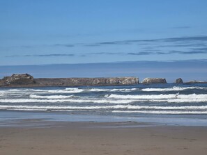 A beach with waves, a rocky outcrop, and a clear sky. - Cozy Cottage by the Sea (Brookings)