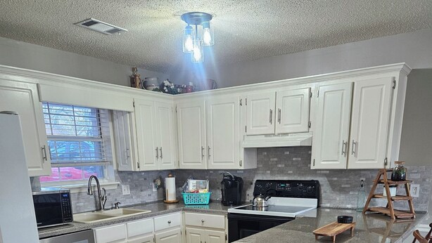 A modern kitchen with white cabinets, a central island with bar stools, a built-in oven, and a microwave. - 3bd/2bth Home, king/queen bds,crib, RV/trailer parking, pet fence, massage chair (Cabot)